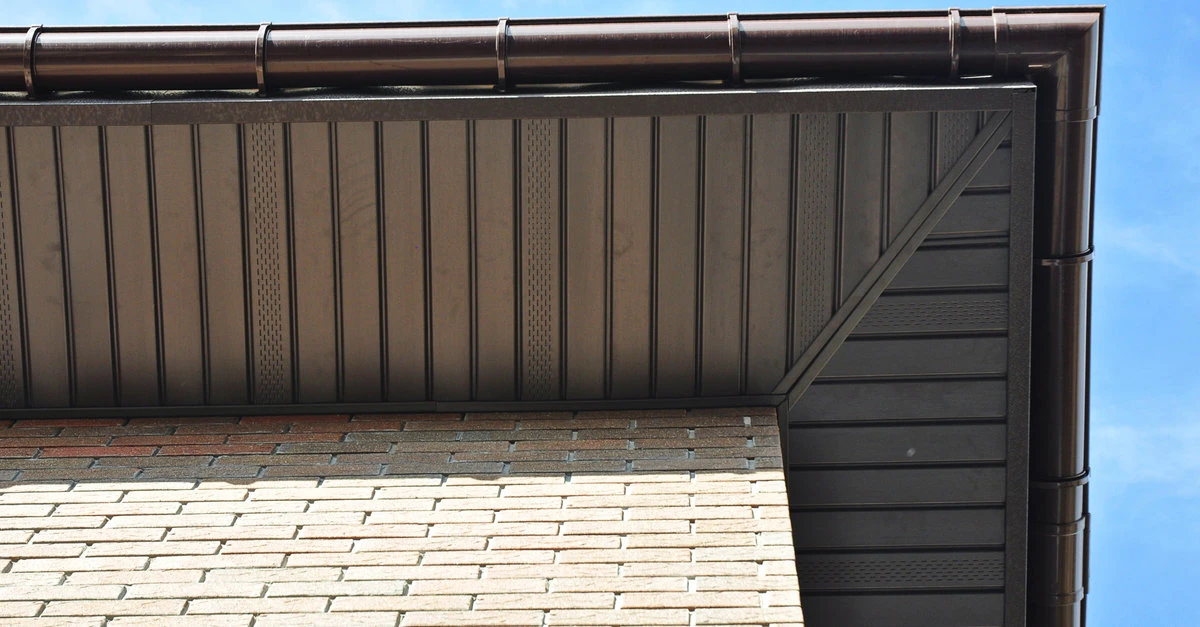 The soffits of a residential roofline that has received soffit service viewed from the ground looking up toward the roof.