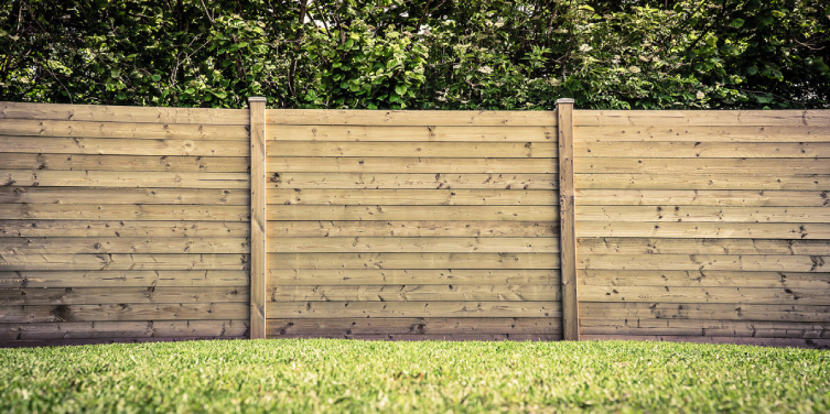 A wooden fence with a natural color after it has been built on a lawn using professional fence installation service.