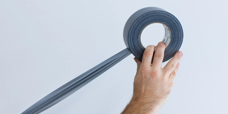 Photo of a hand holding an unrolling duct tape roll