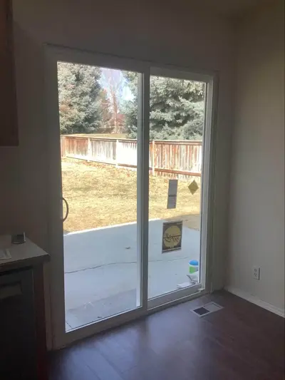 A photo taken from the inside of the house looking out onto the yard through a newly installed sliding glass door.