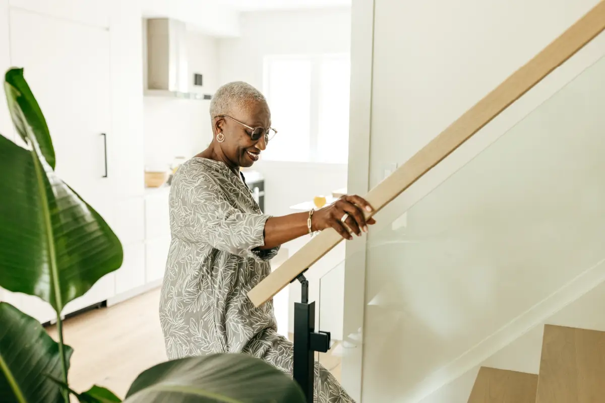 Older woman walking up the stairs in her home.