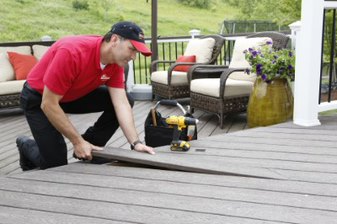 A Mr. Handyman technician fitting a piece of wood into a deck.