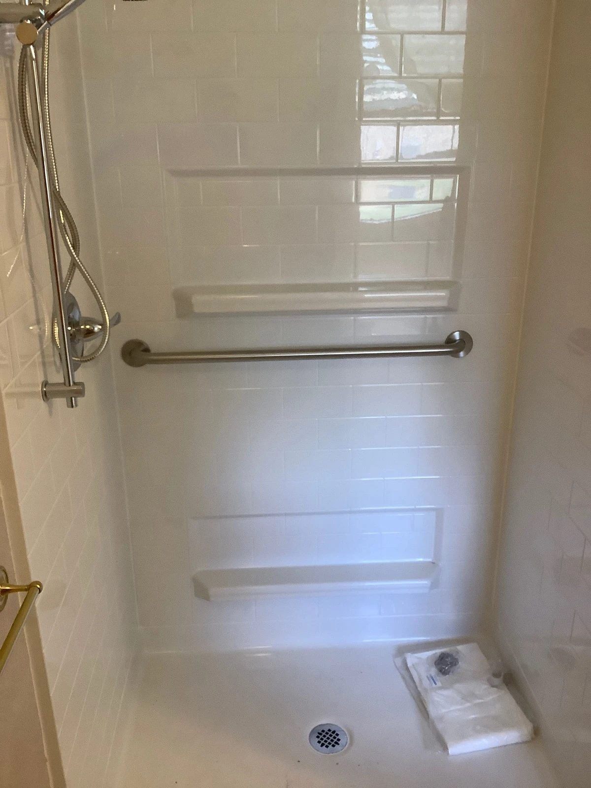 A residential shower that has had a grab bar and detachable shower head installed by Mr. Handyman.