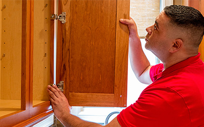 A Mr. Handyman technician fixing a cabinet.