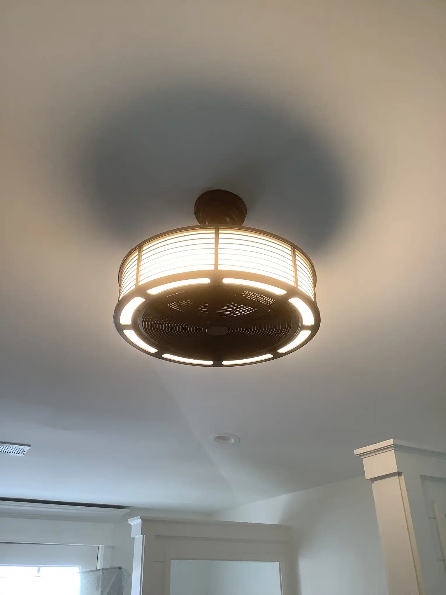 A new ceiling fan installed by Mr. Handyman with a ring of lights around its edge and a wire mesh covering the fan blades.