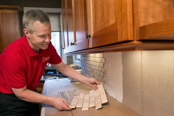 A handyman installing a new tile backsplash during a Wichita kitchen remodeling project.