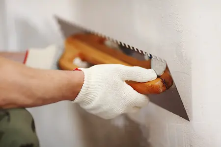 hands adding plaster to wall