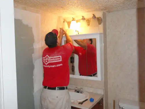 Mr. Handyman technician replacing bathroom light fixture.