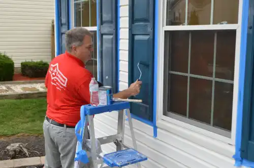 Mr. Handyman technician painting window shutters.