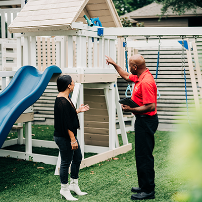 Mr. Handyman standing beside playhouse.