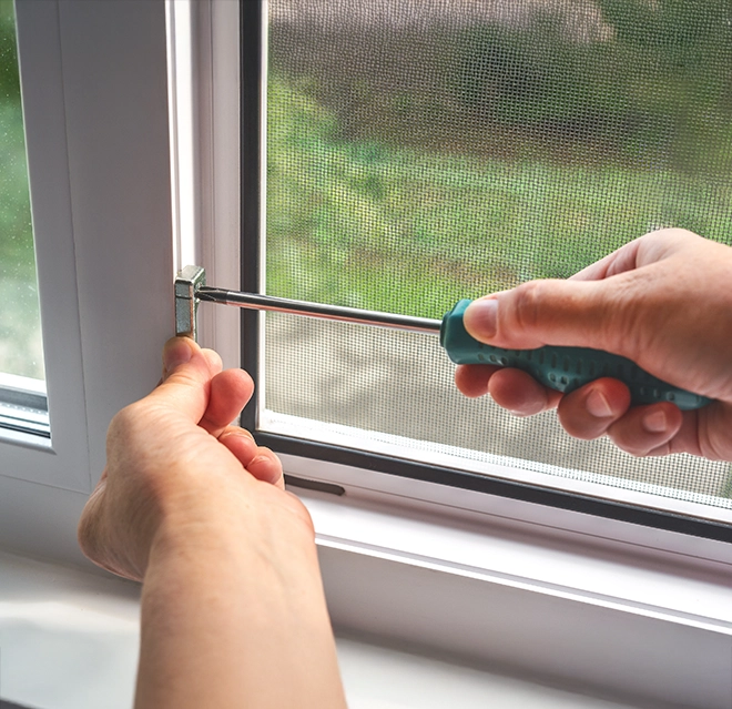 Mr. Handyman using screwdriver on window frame.