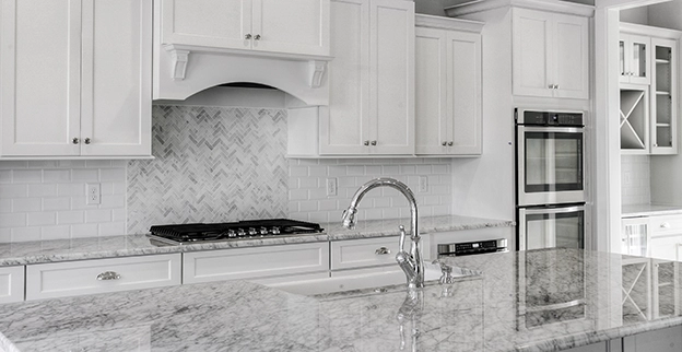 Modern white kitchen with marble countertop.