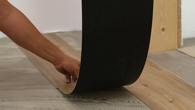 Worker laying a vinyl strip of flooring.