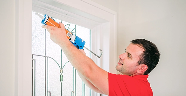 Mr. Handyman caulking stained glass window.