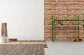 White wall next to brick wall with wood flooring in progress.