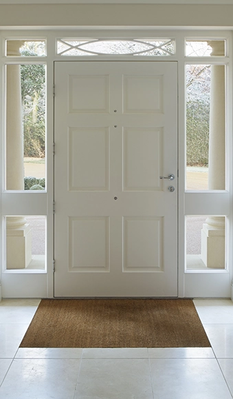 Front door of a home surrounded by windows.