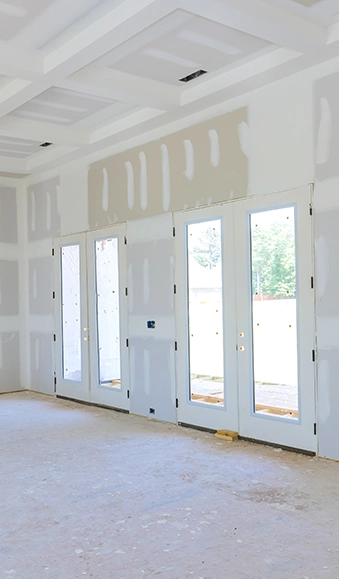 Drywall in room with tall windows.