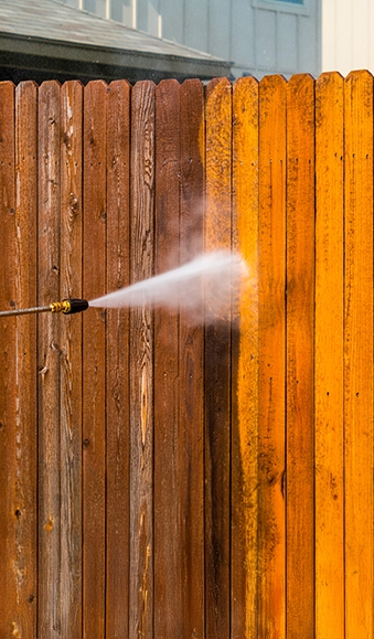 Power washing a wood fence.