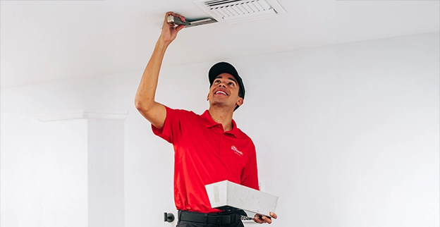 A person used a scraping knife to spread spackle on a ceiling.