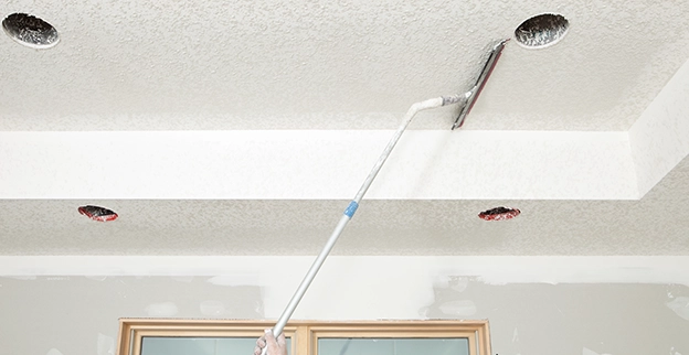 A picture of a painter adding texture to a ceiling.
