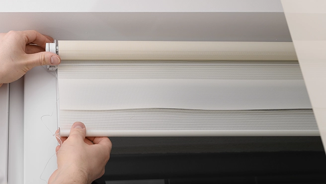 A picture of a person pulling down hanging blinds.