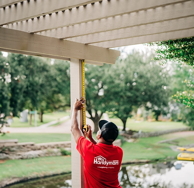 MRH employee measuring a wooden pillar outdoors.