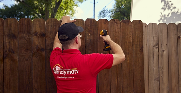 Mr. Handyman technician repairing a wooden fence.