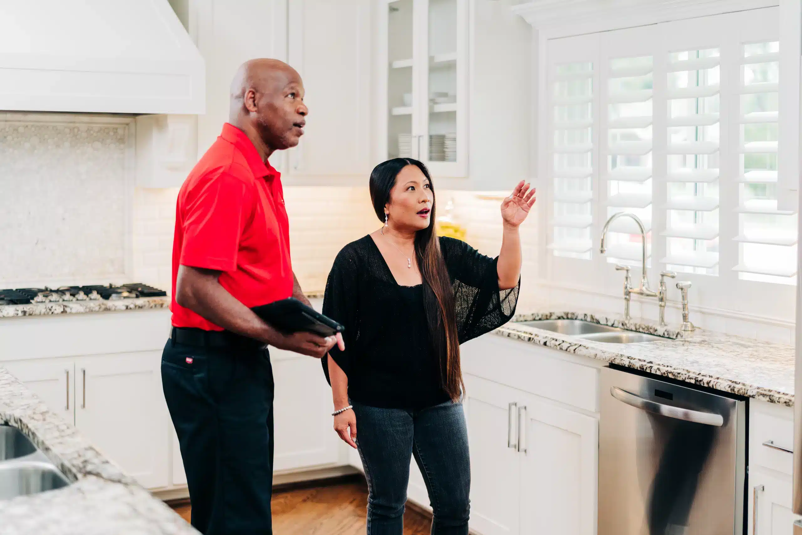 A homeowner discussing a kitchen repair project with a Mr. Handyman service professional.
