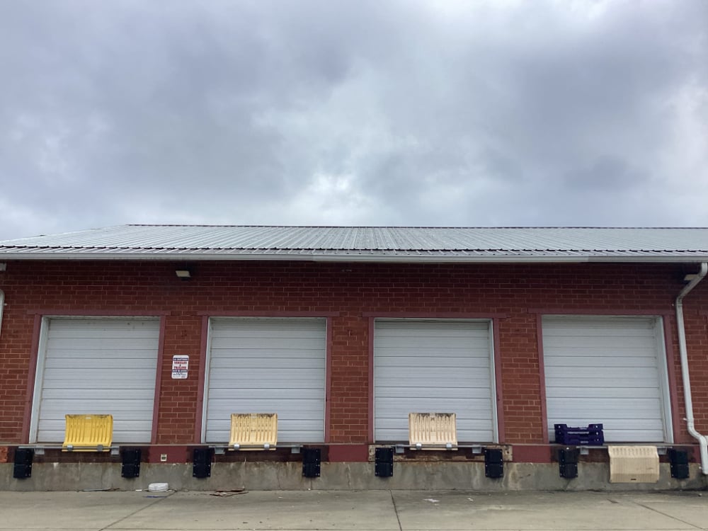 Front view of a red brick commercial building showing repaired soffit and fascia sections with fresh white trim in the center, restored by Mr. Handyman of South Charlotte to fix wood rot and damage.