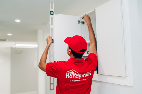 A service professional from Mr. Handyman (Westmont, IL) installing a cabinet door.
