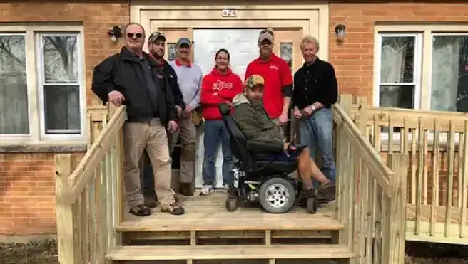 Mr. Handyman of Waukesha team poses with veteran on newly built stairs and wheelchair ramp at veteran's home.