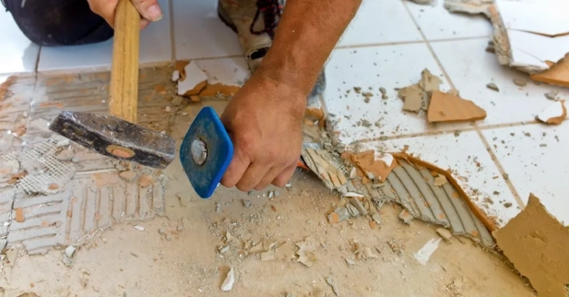 A handyman using a chisel to remove damaged tiles during an appointment for tile repair in Vancouver, WA