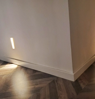 Minimalist interior featuring a corner wall with subtle indirect lighting.