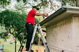 Employee on a ladder near the outdoor roof.