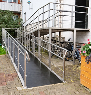 A sturdy, accessible ramp with stainless steel railings leads to a building entrance.