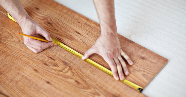  A handyman using a tape measure to measure out material for flooring installation in Wichita, KS.
