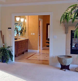 View of a warmly lit bathroom through an open doorway.
