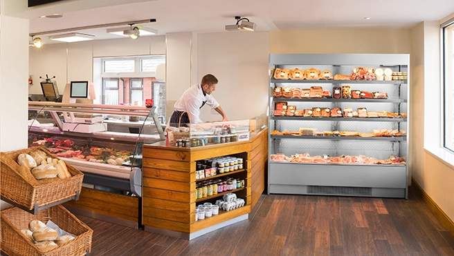 A butcher shop interior featuring a male butcher arranging food items.