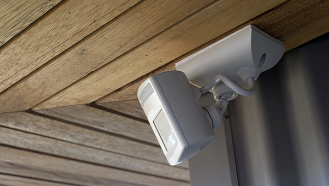 A security camera mounted on a wooden ceiling to capture the view.