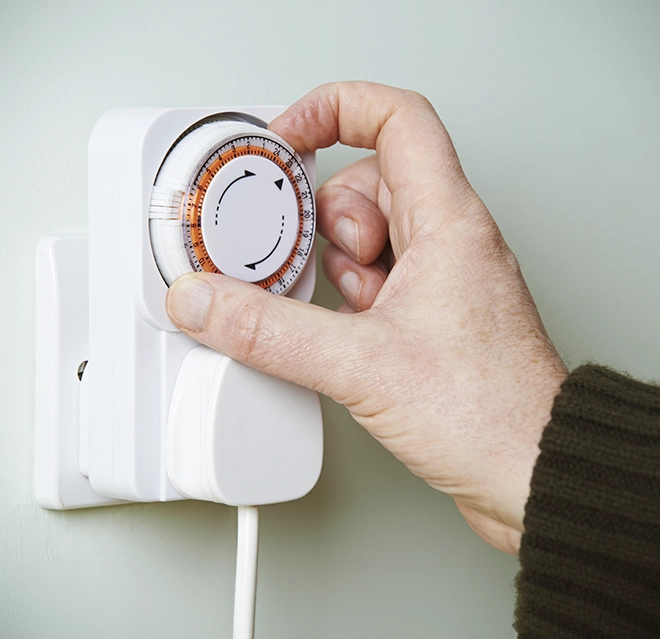 Adjusting a mechanical timer switch mounted on a wall.