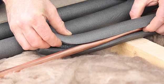 A hand adjusts gray fabric over two foam tubes.