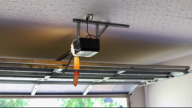 A garage door opener installed on the ceiling with cables.