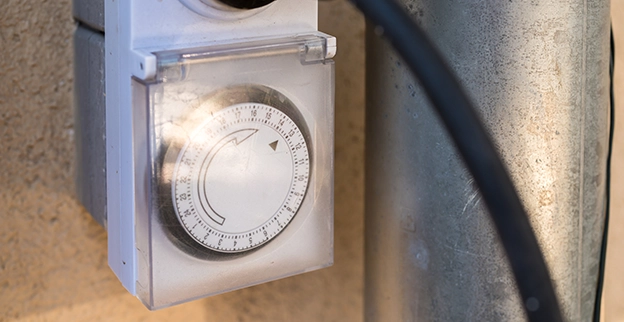 A close-up of a mechanical timer switch mounted on a wall.