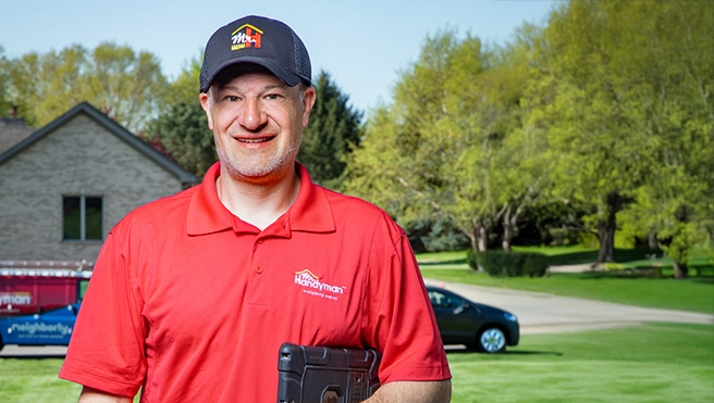 A handyman holds a tablet outside a home.