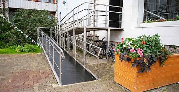 A wheelchair ramp with metal railings leads to a building.