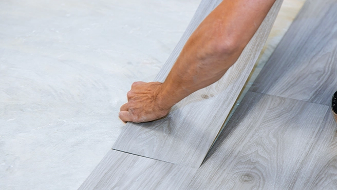 Handyman installing laminate flooring to align a plank with the existing floor.