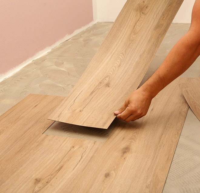 Handyman holding a wooden floor plank.