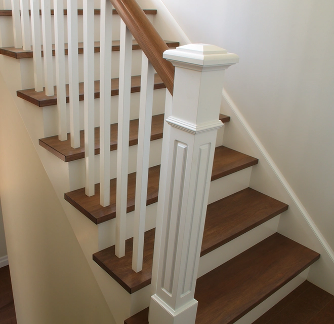 A wooden staircase with elegant banisters and white railings.