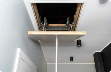 A retractable attic ladder being opened.