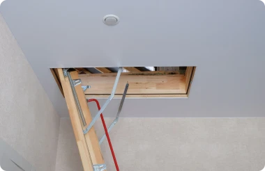 A ceiling hatch with a partially unfolded attic ladder.